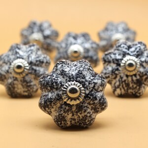 以下が含まれることがあります： 中央に銀色の金属製のアクセントが付いた、黒と白のセラミック製のノブが7つ。ノブは、ざらざらとした斑点のある仕上げになっています。