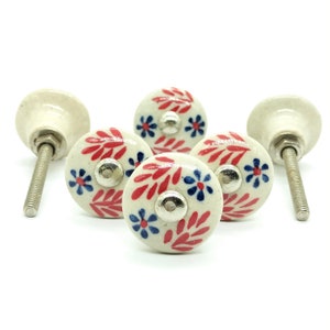 May include: Five white ceramic knobs with red and blue floral designs. The knobs have a silver screw and are perfect for adding a touch of farmhouse style to your home decor.