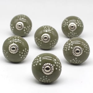 Pode incluir: Seis botões de cerâmica verde com bolinhas brancas e detalhes prateados.