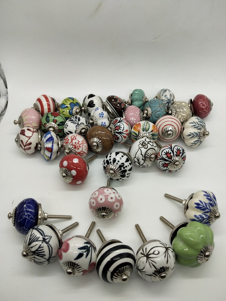 May include: Assortment of colourful ceramic cabinet knobs with various floral and geometric patterns. The knobs have a silver metal base and are perfect for adding a touch of vintage charm to any home decor.