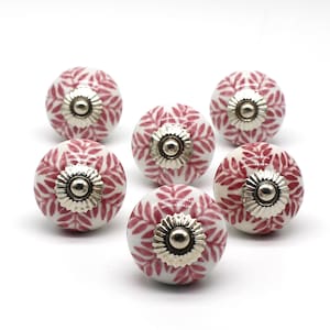 Może przedstawiać: Sześć białych ceramicznych gałek do szafek z różowym wzorem kwiatowym i srebrnymi akcentami.