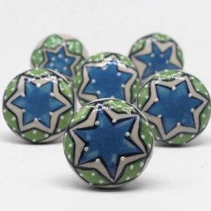 May include: Six ceramic knobs with a green and white background and a blue star design. The stars have white dots on them.