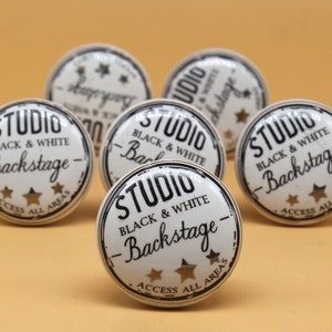 May include: Six white ceramic knobs with black and gold lettering. The knobs feature the text "Studio Black & White - Backstage - Access All Areas".