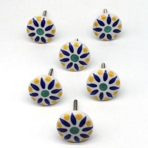 May include: Set of six ceramic drawer knobs with a white background and a blue and yellow floral design. The knobs have a silver screw.