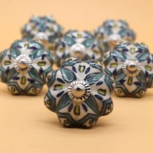 May include: Set of six ceramic cabinet knobs with a white background and a blue and green floral pattern. Each knob has a silver metal base.