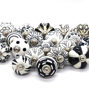 Könnte beinhalten: Eine Sammlung von 18 schwarzen und weißen Keramik-Schrankknöpfen mit verschiedenen floralen und geometrischen Mustern.
