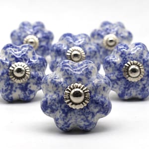 May include: Six blue and white ceramic cabinet knobs with silver accents. Each knob has a scalloped edge and a floral design.