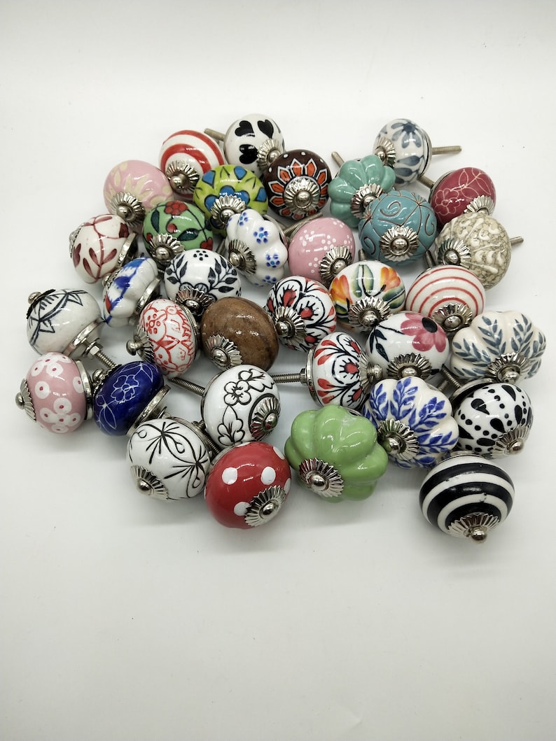 May include: A collection of colourful ceramic cabinet knobs with various floral, geometric, and abstract designs. The knobs have a silver metal base and are perfect for adding a touch of whimsy to any home decor.