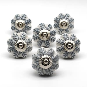 May include: Six white ceramic cabinet knobs with a blue floral design and silver accents.