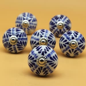 May include: Six white ceramic cabinet knobs with a blue and white floral pattern. The knobs have a silver metal base.