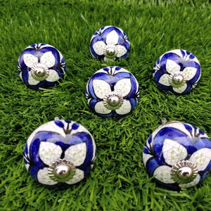 Peut inclure: Six boutons en céramique bleu et blanc avec un motif floral. Les boutons ont un centre en métal argenté.