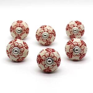Peut inclure: Six boutons de porte en céramique blanche avec un motif floral rouge et des accents argentés.