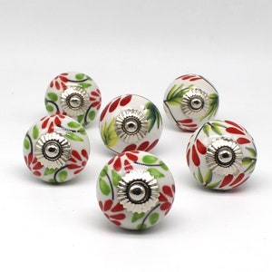 Puede incluir: Conjunto de 6 pomos de armario de cerámica con base blanca y diseños florales rojos y verdes. Cada pomo tiene una base de metal plateado.