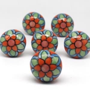May include: Six round ceramic knobs with a floral design. The knobs are painted in shades of orange, green, and blue.