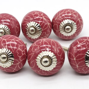 Peut inclure: Ensemble de six boutons de cabinet en céramique rose avec un motif floral blanc et des accents argentés.