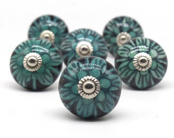 May include: Six teal and black ceramic cabinet knobs with silver accents. Each knob features a floral design.