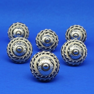Peut inclure: Ensemble de six boutons de cabinet en céramique noir et blanc avec des accents argentés. Chaque bouton présente un motif en spirale et un centre surélevé.
