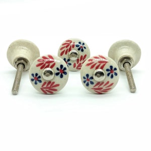 May include: Four white ceramic cabinet knobs with red and blue floral designs and silver accents. Each knob has a silver screw.