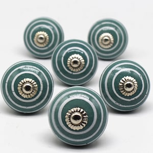 Op de afbeelding: Zes groene en witte gestreepte keramische knoppen met zilveren accenten. De knoppen zijn rond en hebben een verhoogd midden.