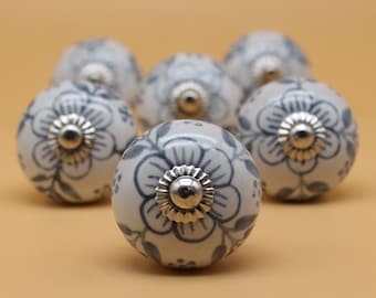 May include: Six white ceramic drawer knobs with a blue floral design and silver accents.