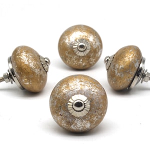 May include: Four gold and silver ceramic cabinet knobs with a distressed finish. Each knob has a silver metal base and a decorative silver metal ring around the center.
