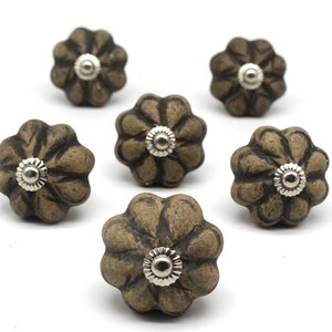May include: Six brown ceramic cabinet knobs with a flower design and silver metal accents.