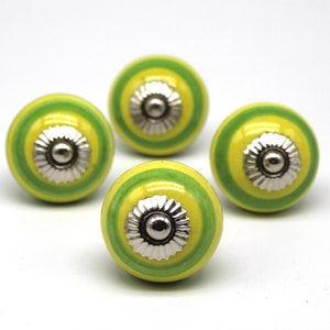 May include: Four green and yellow striped ceramic knobs with silver accents. The knobs are round and have a raised center.