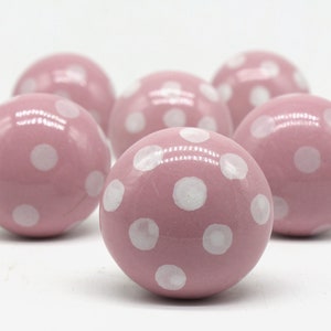 May include: Six pink ceramic knobs with white polka dots.