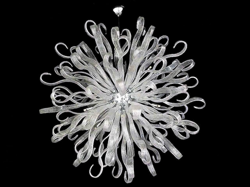 May include: A large, modern chandelier made of clear glass. The chandelier has a starburst design with many long, thin glass pieces that curve and twist. The chandelier is suspended from a single point in the ceiling.