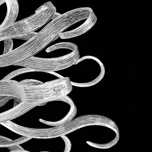 May include: A silver chandelier with a unique design featuring multiple curved, twisted glass arms.