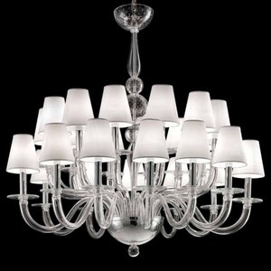 May include: A clear glass chandelier with multiple arms and white lampshades. The chandelier has a central stem with decorative glass elements and a large, round base. The lampshades are conical and evenly spaced around the fixture.