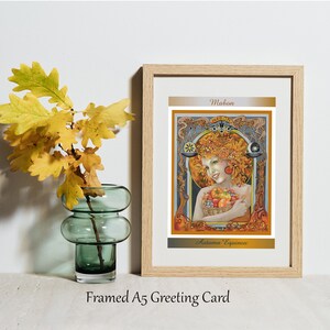May include: Framed A5 greeting card with an art nouveau illustration of a woman surrounded by autumn leaves and fruit. The card is in a wooden frame and has the text "Mabon" and "Autumn Equinox". A green glass vase holds yellow oak leaves.