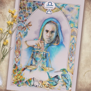 May include: Watercolour illustration of the Libra zodiac sign. A person in a blue hooded robe holds scales. The card features butterflies, birds, and the Libra symbol. The word "Libra" is written at the bottom.