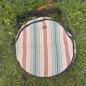 Può includere: Una borsa rotonda con motivo bianco e nero con una tracolla nera. La borsa ha una chiusura a zip ed è realizzata in tessuto intrecciato.