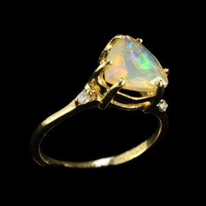 May include: A gold ring with a heart-shaped opal gemstone and two small diamonds on the band.