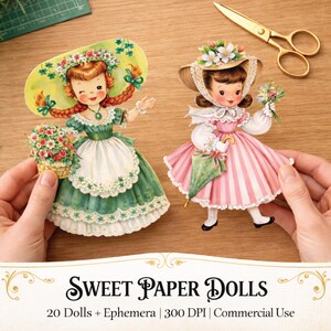Puede incluir: Dos mu&ntilde;ecas de papel vintage, una con un vestido verde con sombrero floral y otra con un vestido rosa a rayas, se sostienen sobre una superficie de madera. El texto "Sweet Paper Dolls" se muestra debajo.