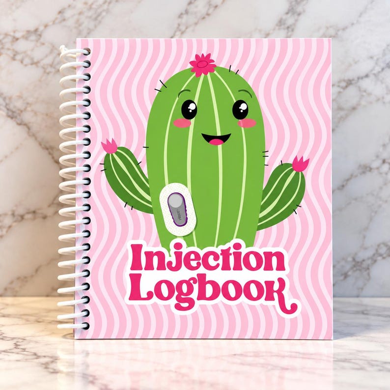 May include: A spiral-bound logbook with a pink and white wavy background. The cover features a green cartoon cactus with a smiling face, pink flowers, and a small medical device graphic. The text Injection Logbook is printed in bold pink.