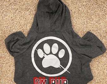 Puede incluir: Suéter gris con capucha para perro con una huella de pata blanca dentro de un círculo con una línea diagonal que lo atraviesa. El texto "CM PUP" está impreso en rojo y blanco debajo de la huella de pata.
