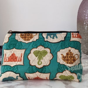 May include: Teal quilted zippered pouch with a colorful print of elephants, teapots, and buildings. The print is on a cream background with teal accents.