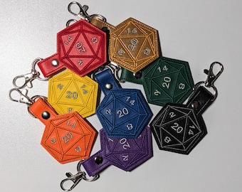 May include: A set of eight colorful leather dice charms with a 20-sided design. Each charm features white embroidery with the numbers 2, 8, 14, and 20. The charms are attached to key rings.