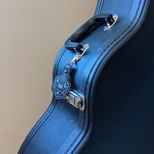 The black vinyl D20 keychain clipped onto a guitar case.