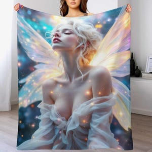 May include: A soft, plush blanket featuring a digital art print of a fairy with blonde hair and large, iridescent wings. The fairy is depicted with closed eyes and a serene expression, surrounded by sparkling lights against a blue and teal background.