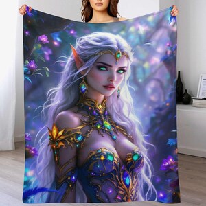 May include: A plush blanket featuring a fantasy illustration of a woman with long white hair, pointed ears, and green eyes. She wears a blue and gold jeweled gown. The background includes purple flowers and a forest setting.
