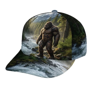 Può includere: Un cappellino da baseball con una stampa grafica a colori di una grande creatura pelosa con segni tribali scuri e complessi, in piedi in una foresta lussureggiante accanto a un fiume con montagne innevate visibili sullo sfondo lontano.