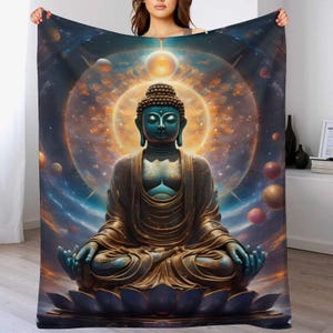 May include: A plush blanket featuring a serene Buddha statue in a meditative pose. The Buddha is depicted with a teal complexion and is surrounded by a cosmic background of swirling colors, planets, and a bright golden halo. The blanket is a soft, cozy home decor item.