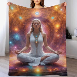 May include: A soft blanket featuring a woman meditating in a lotus position. The blanket's background is a vibrant, colorful depiction of a spiritual mandala with swirling patterns in shades of orange, gold, blue, and purple.