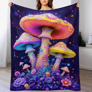May include: A vibrant blanket featuring a colorful illustration of psychedelic mushrooms against a dark blue starry background. The mushrooms have pink, yellow, and blue caps with intricate patterns. Flowers and foliage surround the mushrooms, adding to the whimsical design.