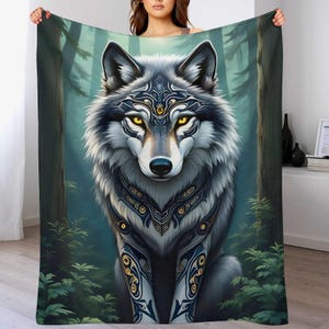 May include: A blanket featuring a detailed illustration of a wolf with yellow eyes and intricate blue and gold patterns. The wolf is set against a backdrop of a forest with tall trees and lush greenery. The blanket is held up, showcasing the design.