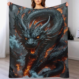 May include: A black dragon blanket with fiery orange accents and glowing eyes. The dragon is the central focus, surrounded by smoke and flames. The blanket is held up, showcasing the detailed artwork.