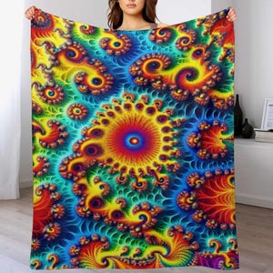 May include: A vibrant, colorful blanket with a psychedelic spiral design. The blanket features a central sunburst pattern in red, yellow, and orange, surrounded by swirling blue, green, and yellow spirals. The blanket is soft and inviting.